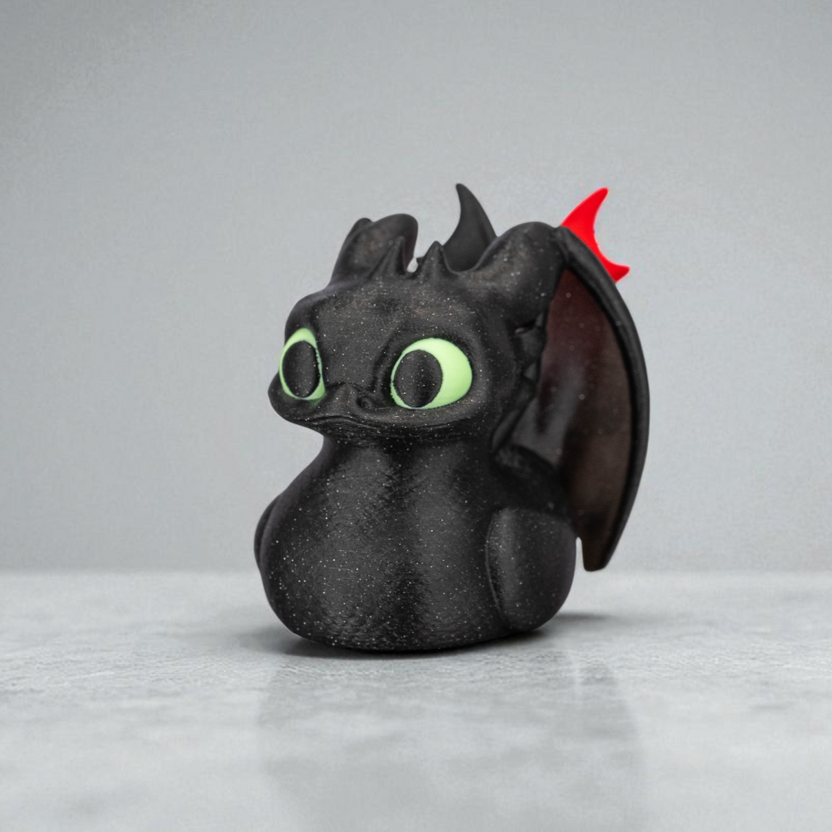 Toy figure of a dragon with green eyes and red horn on a gray background