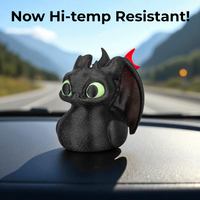 Black dragon figurine with green eyes on a car dashboard, text 'Now Hi-temp Resistant!' above.